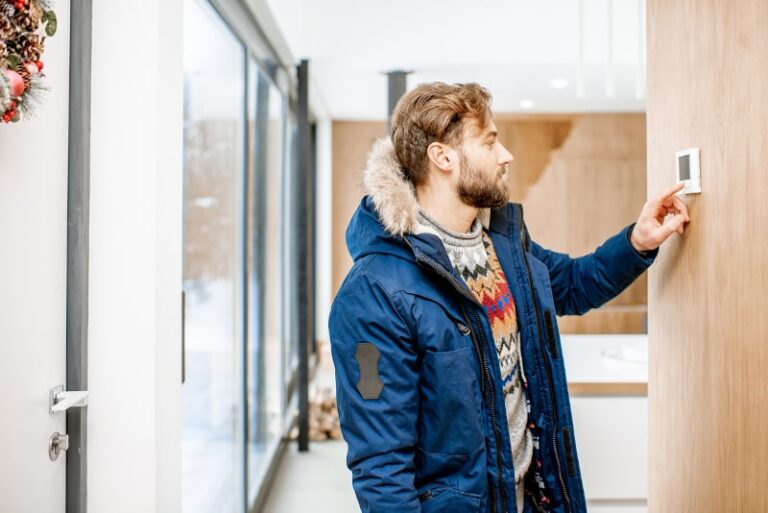 Cold Man Adjusting Heat Pump Thermostat